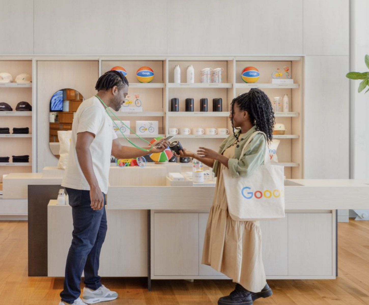 Store assistant handing a product to a customer at the checkout counter in a Google retail store